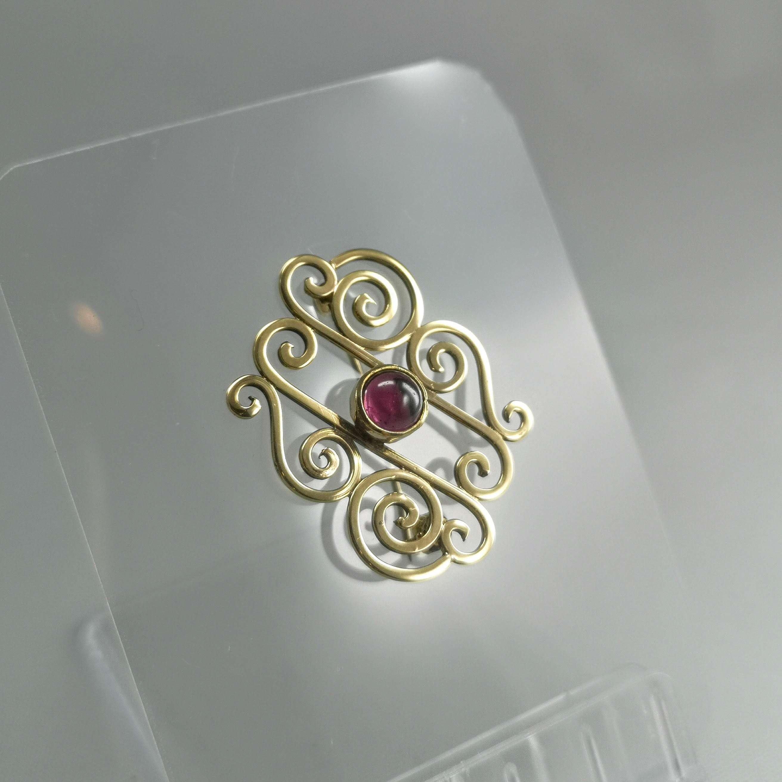 9ct Gold celtic spiral brooch with a garnet stone